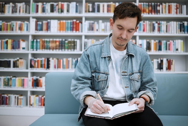 Estudiante universitario, hombre, biblioteca, y, escritura, en, sofá, con, ideas, visión, y, enfoque, en, educación, en, academia, salón, universidad, pluma, y, cuaderno, para, notas, objetivos, y, estudiar, para, examen, investigación, y, tarea