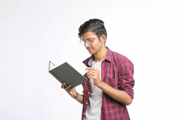 Estudiante universitario indio de pie con bolsa y leyendo productos lácteos sobre fondo blanco.