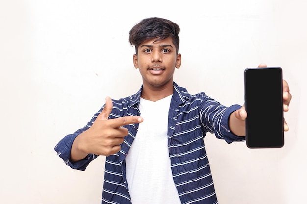 Estudiante universitario indio que muestra la pantalla móvil sobre fondo blanco.