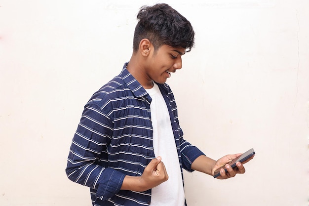 Estudiante universitario indio con smartphone sobre fondo blanco.