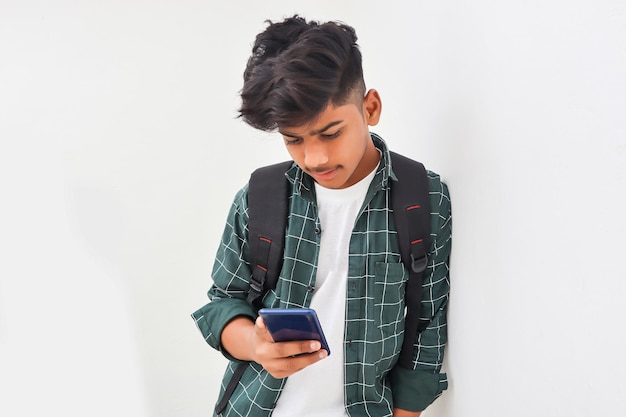 Estudiante universitario indio usando un teléfono inteligente con fondo blanco.