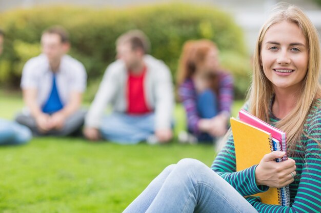 Estudiante universitario sonriente con amigos borrosos en el parque