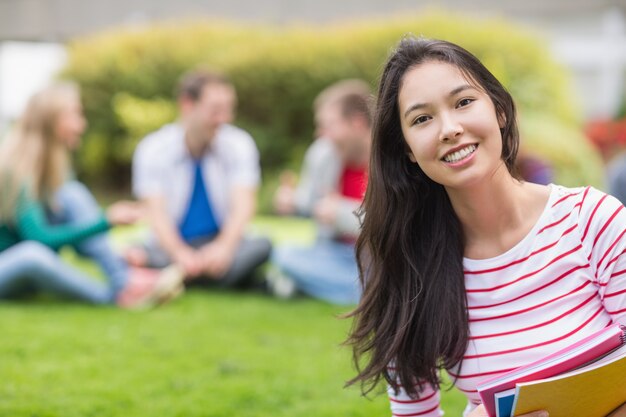 Estudiante universitario sonriente con amigos borrosos en el parque