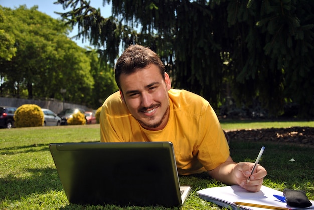 Estudiante universitario tumbado en la hierba en el sol