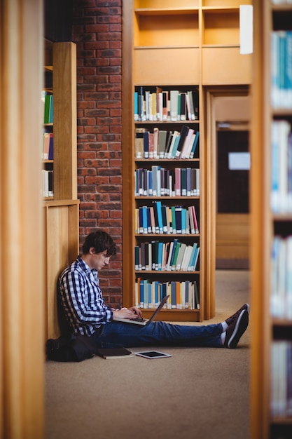 Foto estudiante usando una computadora portátil en la biblioteca