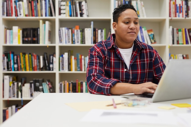 Estudiante usando una computadora portátil en la biblioteca