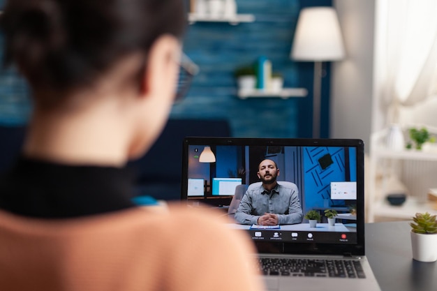 Foto estudiante usando laptop para videollamada con el maestro. candidato que asiste a una entrevista en línea con el empleador. freelancer trabajando desde casa en videollamada con cliente. videoconferencia webinar online.