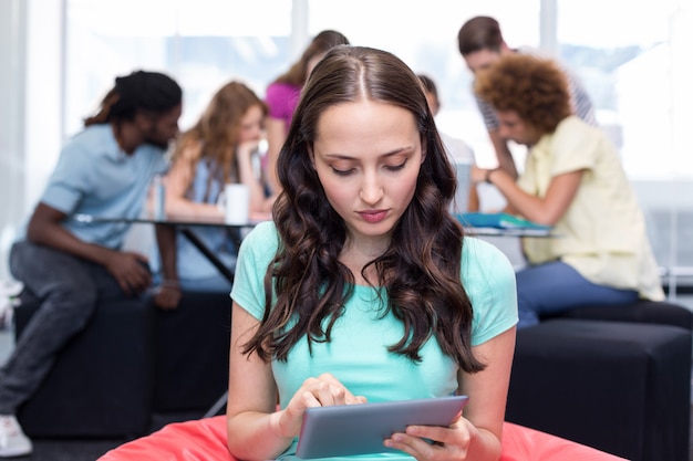 Foto estudiante usando tableta digital con amigos en el fondo