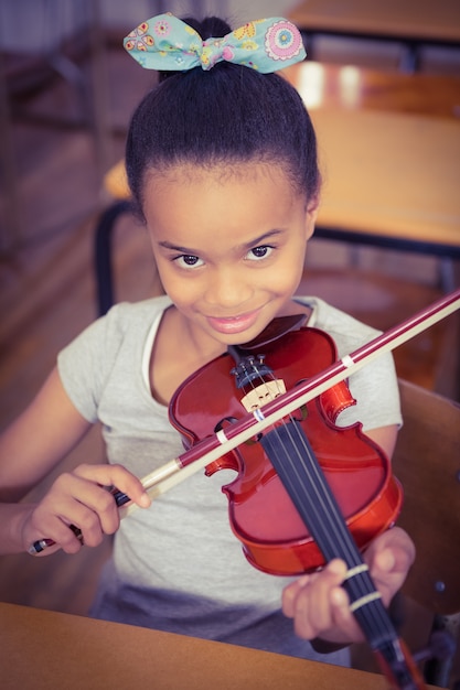 Foto estudiante usando un violín en clase