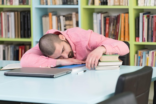 Foto estudiante varón durmiendo en la biblioteca