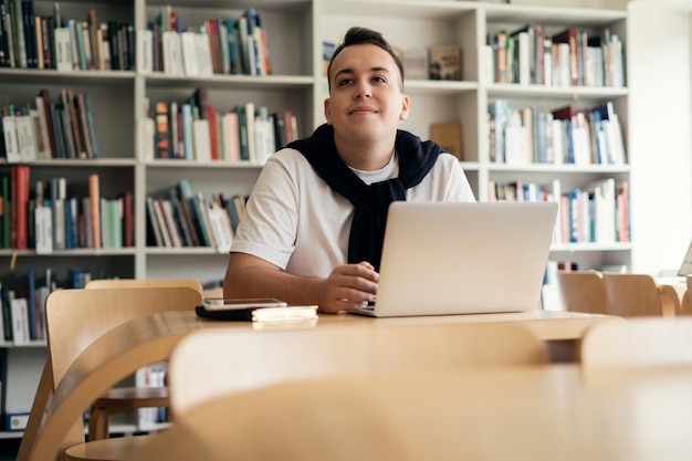 Estudiante varón de lección en línea que estudia en la universidad usa un chat de video portátil se sienta en una sala de conferencias