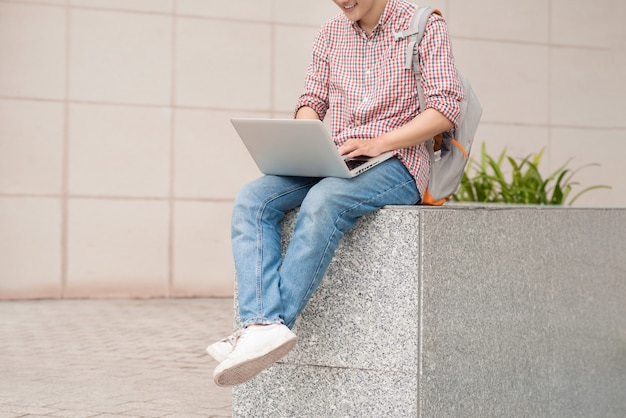 Estudiante varón usando laptop en campus universitario