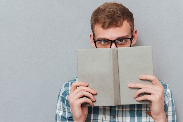 Estudiante en vasos con libro aislado en gris