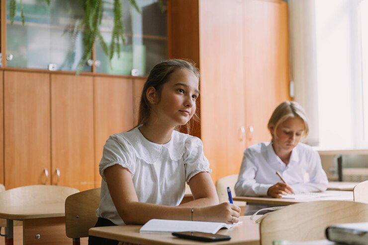 Estudiantes adolescentes escribiendo en un cuaderno en el escritorio en el aula trabajando en la lección