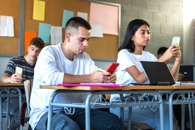 estudiantes adolescentes de secundaria que usan el teléfono en clase para usar aplicaciones de redes sociales y tomarse selfies