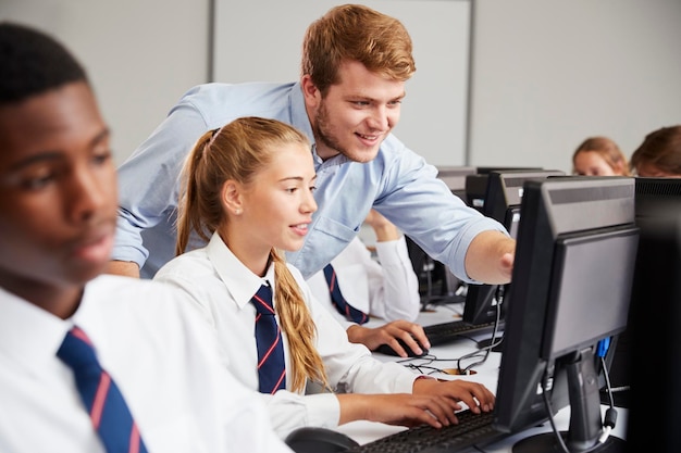 Estudiantes adolescentes con uniforme estudian en la clase de TI