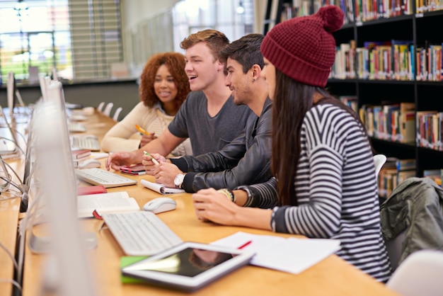 Estudiantes y amigos de la biblioteca con computadora en la universidad para el aprendizaje educativo o la discusión sobre el proyecto Colegio en línea y estudiantes diversos para el conocimiento de becas o trabajando en una asignación