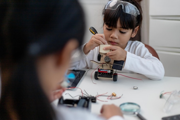 Los estudiantes de Asia aprenden en casa en la codificación de coches robóticos y cables de placa electrónica en STEM STEAM matemáticas ingeniería ciencia tecnología código de computadora en robótica para niños concepto