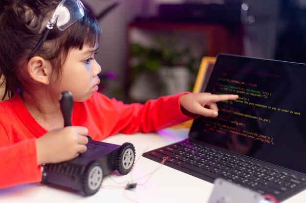 Los estudiantes de Asia aprenden en casa en la codificación de coches robóticos y cables de placa electrónica en STEM STEAM matemáticas ingeniería ciencia tecnología código de computadora en robótica para niños concepto