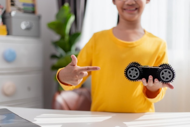 Los estudiantes de Asia aprenden en casa codificando autos robot y cables de placas electrónicas en STEM STEAM matemáticas ingeniería ciencia tecnología código informático en robótica para niños concepto