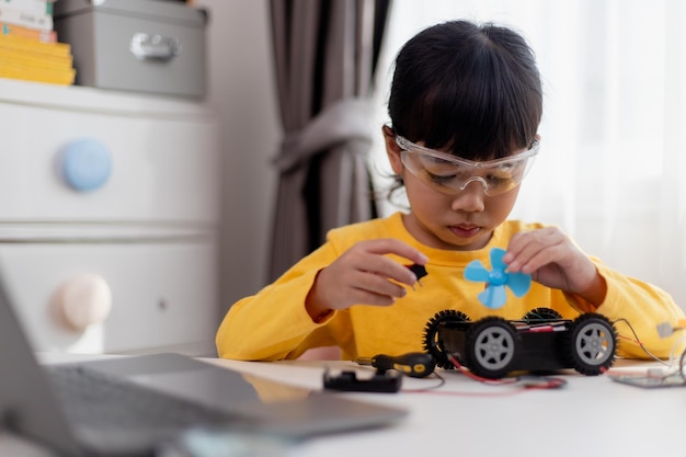 Los estudiantes de Asia aprenden en casa codificando autos robot y cables de placas electrónicas en STEM STEAM matemáticas ingeniería ciencia tecnología código informático en robótica para niños concepto