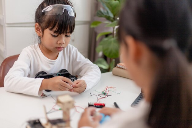 Los estudiantes de Asia aprenden en casa codificando autos robot y cables de placas electrónicas en STEM STEAM matemáticas ingeniería ciencia tecnología código informático en robótica para niños concepto