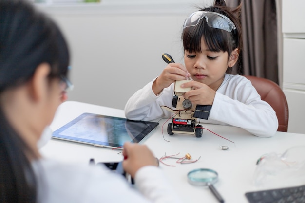 Los estudiantes de Asia aprenden en casa codificando autos robot y cables de placas electrónicas en STEM STEAM matemáticas ingeniería ciencia tecnología código informático en robótica para niños concepto