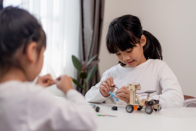 Los estudiantes de Asia aprenden en casa codificando autos robot y cables de placas electrónicas en STEM STEAM matemáticas ingeniería ciencia tecnología código informático en robótica para niños concepto