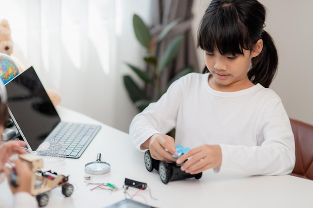 Los estudiantes de Asia aprenden en casa codificando autos robot y cables de placas electrónicas en STEM STEAM matemáticas ingeniería ciencia tecnología código informático en robótica para niños concepto