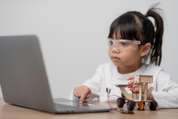 Los estudiantes de Asia aprenden en casa codificando autos robot y cables de placas electrónicas en STEM STEAM matemáticas ingeniería ciencia tecnología código informático en robótica para niños concepto