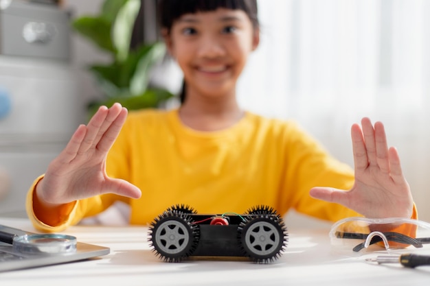 Los estudiantes de Asia aprenden en casa codificando autos robot y cables de placas electrónicas en STEM STEAM matemáticas ingeniería ciencia tecnología código informático en robótica para niños concepto