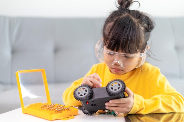 Los estudiantes de Asia aprenden en casa a codificar automóviles robot y cables de placa electrónica en STEM, STEAM, código informático de tecnología de ciencia de ingeniería matemática en robótica para el concepto de niños.