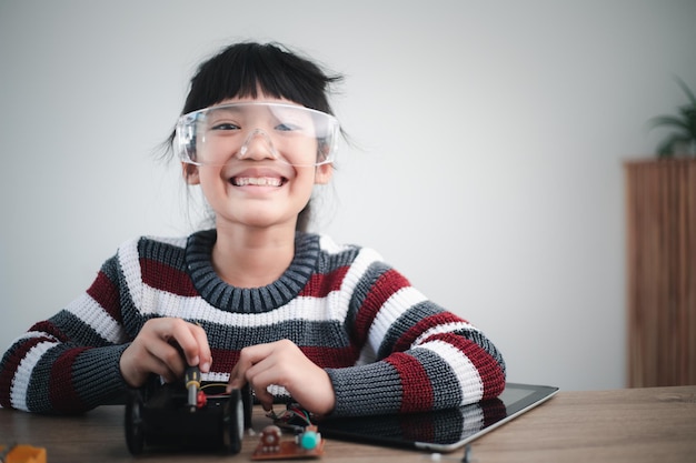 Los estudiantes de Asia aprenden en casa a codificar automóviles robot y cables de placa electrónica en STEM, STEAM, código informático de tecnología de ciencia de ingeniería matemática en robótica para el concepto de niños.