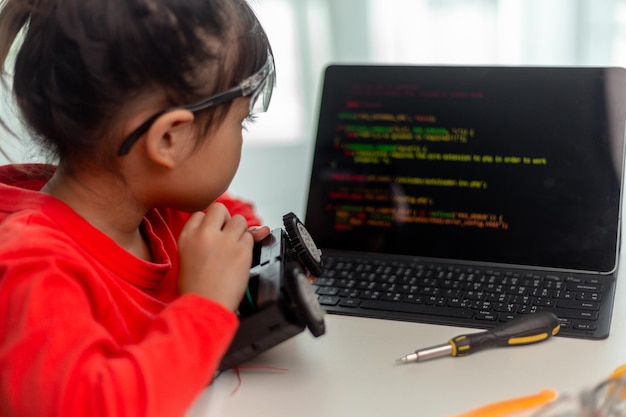 Los estudiantes asiáticos aprenden en casa en la codificación de coches robóticos y cables de placa electrónica en STEM STEAM matemáticas ingeniería ciencia tecnología código informático en robótica para niños concepto
