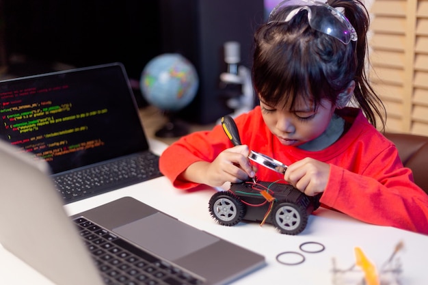 Los estudiantes asiáticos aprenden en casa en la codificación de coches robóticos y cables de placa electrónica en STEM STEAM matemáticas ingeniería ciencia tecnología código informático en robótica para niños concepto