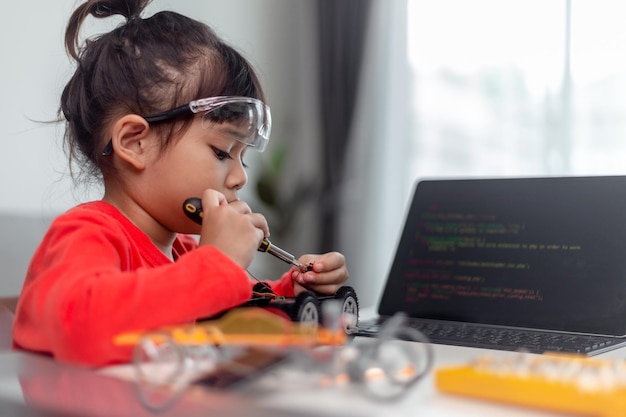 Los estudiantes asiáticos aprenden en casa en la codificación de coches robóticos y cables de placa electrónica en STEM STEAM matemáticas ingeniería ciencia tecnología código informático en robótica para niños concepto