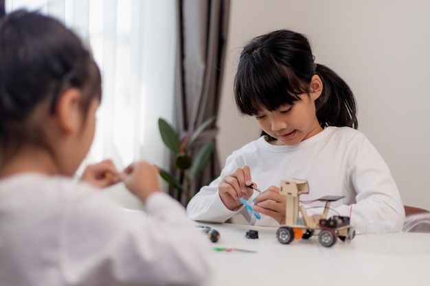 Los estudiantes asiáticos aprenden en casa en la codificación de coches robóticos y cables de placa electrónica en STEM STEAM matemáticas ingeniería ciencia tecnología código informático en robótica para niños concepto