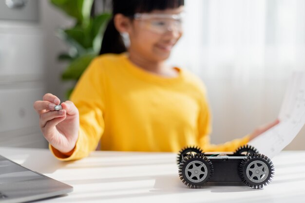 Los estudiantes asiáticos aprenden en casa en la codificación de coches robóticos y cables de placa electrónica en STEM STEAM matemáticas ingeniería ciencia tecnología código informático en robótica para niños concepto