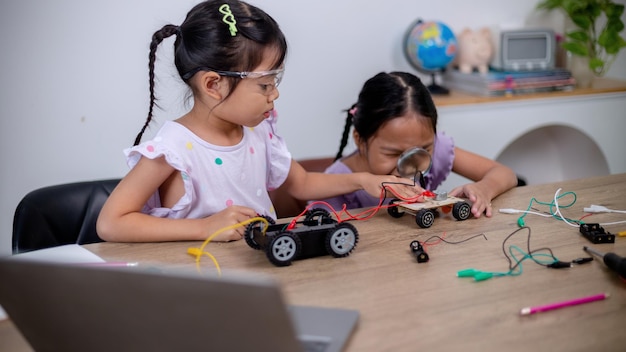 Los estudiantes asiáticos aprenden en casa codificando coches robot y cables de placas electrónicas en STEM STEAM matemáticas ingeniería ciencia tecnología código informático en robótica para conceptos infantiles