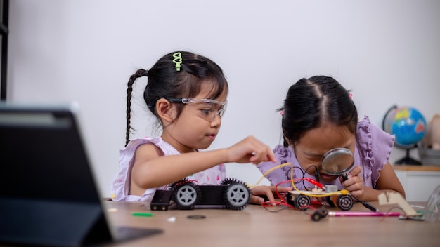 Los estudiantes asiáticos aprenden en casa codificando coches robot y cables de placas electrónicas en STEM STEAM matemáticas ingeniería ciencia tecnología código informático en robótica para conceptos infantiles