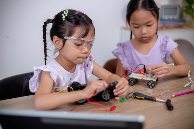 Los estudiantes asiáticos aprenden en casa codificando coches robot y cables de placas electrónicas en STEM STEAM matemáticas ingeniería ciencia tecnología código informático en robótica para conceptos infantiles