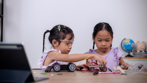 Los estudiantes asiáticos aprenden en casa codificando coches robot y cables de placas electrónicas en STEM STEAM matemáticas ingeniería ciencia tecnología código informático en robótica para conceptos infantiles