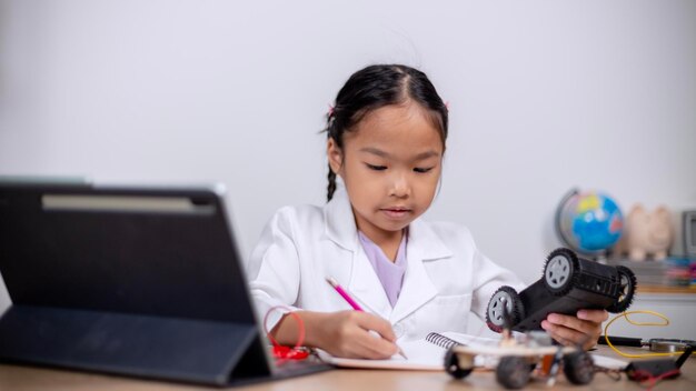 Los estudiantes asiáticos aprenden en casa codificando coches robot y cables de placas electrónicas en STEM STEAM matemáticas ingeniería ciencia tecnología código informático en robótica para conceptos infantiles