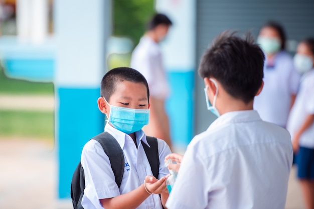 Los estudiantes asiáticos de la escuela primaria usan una máscara médica para prevenir la infección por coronavirus