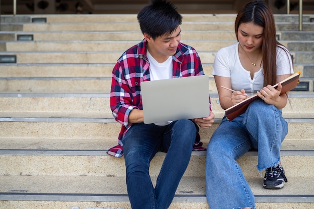 Los estudiantes asiáticos masculinos y femeninos se sientan y revisan el libro de texto, discuten el estudio en su tiempo libre y hacen la tarea en la escuela.