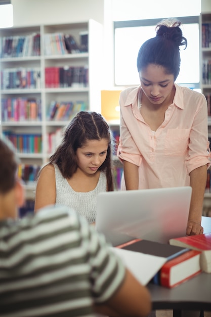 Estudiantes atentos con laptop en biblioteca