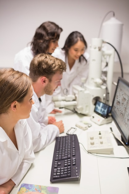 Foto estudiantes de bioquímica que usan microscopio grande y computadora