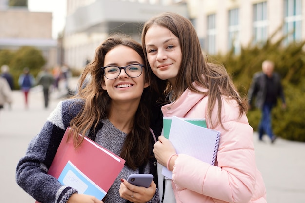 Estudiantes de chicas atractivas alegres que van a casa después de las clases en la universidad