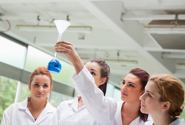 Foto estudiantes de ciencias mirando un matraz