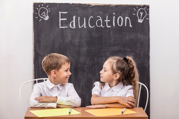 Estudiantes en la clase en el escritorio contra la pizarra